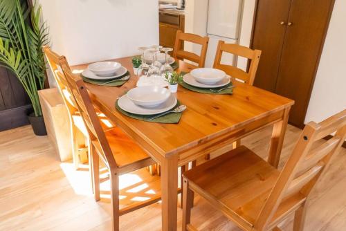 a wooden dining room table with plates and glasses on it at ジブリパークまで車10分 遊べるキッズハウス1棟貸切り 敷地内無料駐車場あり 最大12名 in Seto