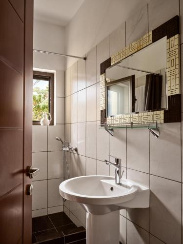 a white bathroom with a sink and a mirror at Rosa Sea Front Maisonette in Alikanas