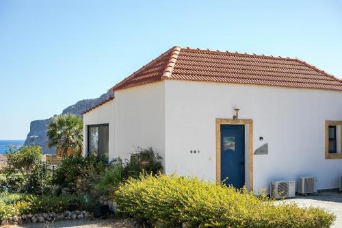 a small white house with a blue door at Villa Pebble in Pefki Rhodes