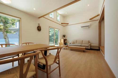 a dining room with a table and chairs and a couch at New Villa Natural Q 城ケ崎海岸 伊豆高原 in Ito