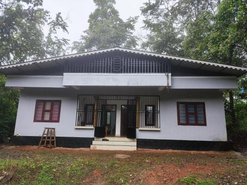a white house with red windows and a ladder at Brahmagiri Homestay Serviced Villa in Thirunelli