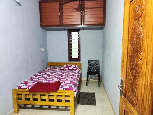a bedroom with a wooden bed and a chair at Brahmagiri Homestay Serviced Villa in Thirunelli