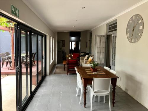 a dining room with a table and a clock on the wall at Vlettershof Guest House in Robertson