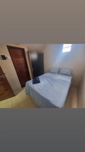 a bedroom with a bed with blue sheets and a door at Pousada Ouro Branco in Macau