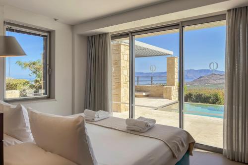 a bedroom with a bed and a view of a pool at Youphoria Sea View Villas in Kissamos