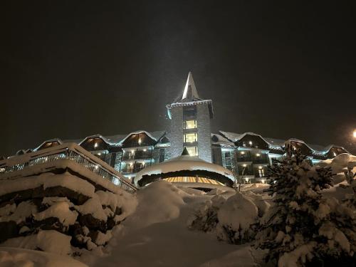 a building with a clock tower in the snow at night at Snö Aragon Hills in Formigal