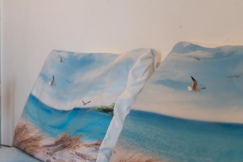 a pillow with a painting of the ocean and birds at Gioiamare in Martinsicuro