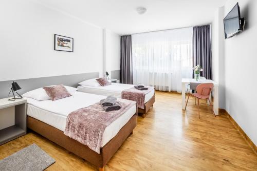 a hotel room with two beds and a desk at Sport Hotel in Jelenia Góra