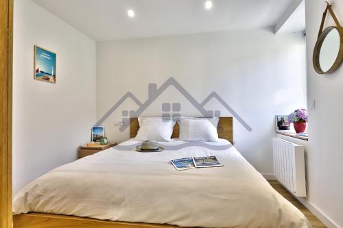 a bedroom with a large bed with white sheets at LocaLise - M44 - Ty Juzolie -Maison de plain-pied avec jardin clos à deux pas du centre, du port et des plages du Guilvinec - Wifi inclus - Linge de lit inclus - Animaux bienvenus in Le Guilvinec