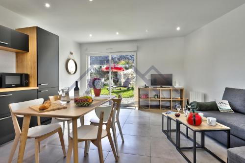 a kitchen and living room with a table and chairs at LocaLise - M44 - Ty Juzolie -Maison de plain-pied avec jardin clos à deux pas du centre, du port et des plages du Guilvinec - Wifi inclus - Linge de lit inclus - Animaux bienvenus in Le Guilvinec