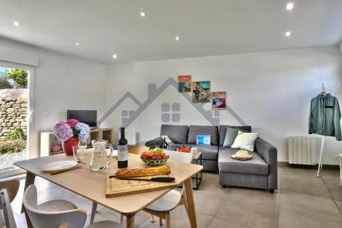 a living room with a table and a couch at LocaLise - M44 - Ty Juzolie -Maison de plain-pied avec jardin clos à deux pas du centre, du port et des plages du Guilvinec - Wifi inclus - Linge de lit inclus - Animaux bienvenus in Le Guilvinec