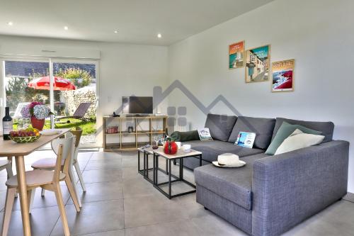 a living room with a gray couch and a table at LocaLise - M44 - Ty Juzolie -Maison de plain-pied avec jardin clos à deux pas du centre, du port et des plages du Guilvinec - Wifi inclus - Linge de lit inclus - Animaux bienvenus in Le Guilvinec