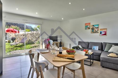 a living room with a table and a couch at LocaLise - M44 - Ty Juzolie -Maison de plain-pied avec jardin clos à deux pas du centre, du port et des plages du Guilvinec - Wifi inclus - Linge de lit inclus - Animaux bienvenus in Le Guilvinec