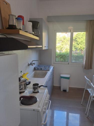 a kitchen with a stove and a sink and a window at Studios Αποστόλης Selianitika in Aígio