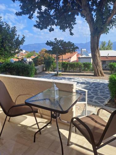a glass table and two chairs on a patio at Studios Αποστόλης Selianitika in Aígio