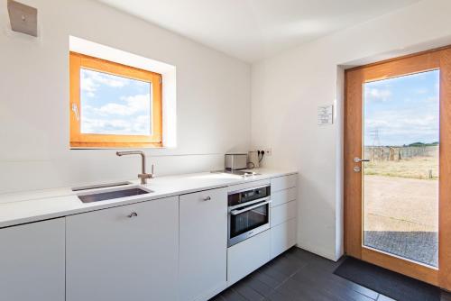a white kitchen with a sink and a window at Fog Signal Building by Bloom Stays in Littlestone-on-Sea