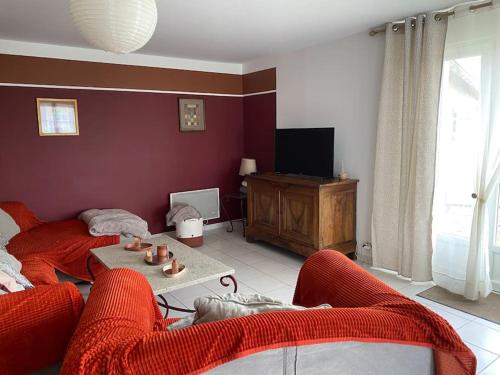 un salon avec un canapé rouge et une télévision dans l'établissement Le Chèvrefeuille, à Cerelles