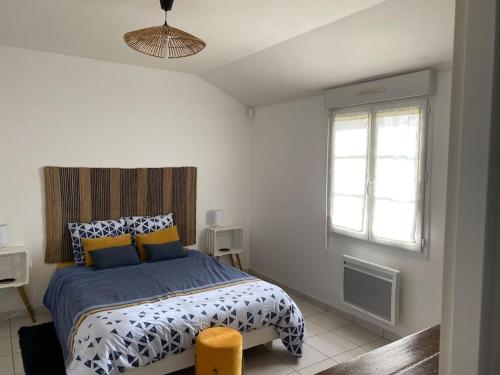 une chambre avec un lit avec des oreillers bleus et jaunes dans l'établissement Le Chèvrefeuille, à Cerelles