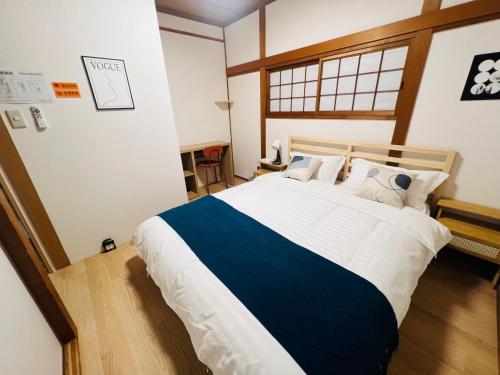 a bedroom with a large bed with blue and white sheets at 旭house in Osaka