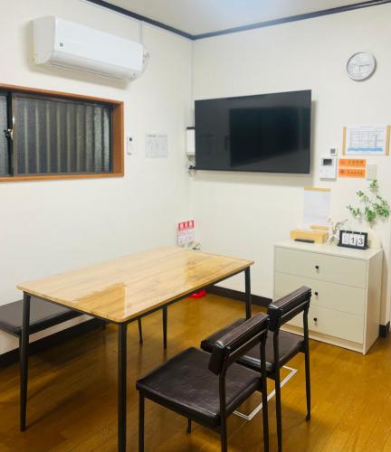 a table and two chairs in a room with a tv at 旭house in Osaka