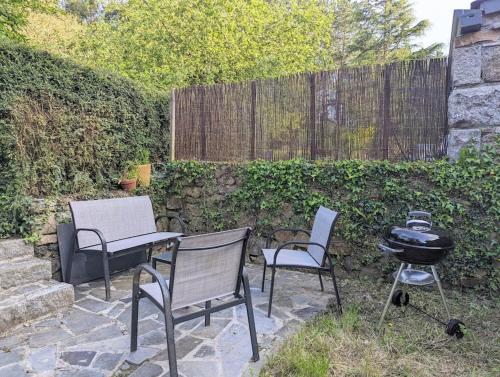 a patio with two chairs and a grill and a smoker at Maison de campagne au bord du ruisseau-5mn mer in Lamballe Armor