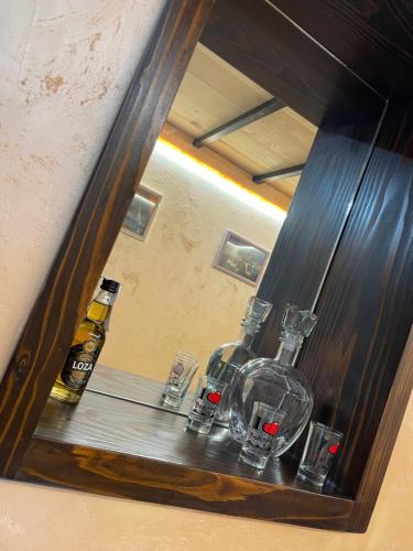 a mirror reflection of a shelf with glasses and bottles at APARTMAN OAZA 24 in Surčin