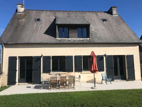 a building with a table and chairs and a red umbrella at Maison rénovée en centre-ville, à 5 min des plages in Beaussais sur Mer