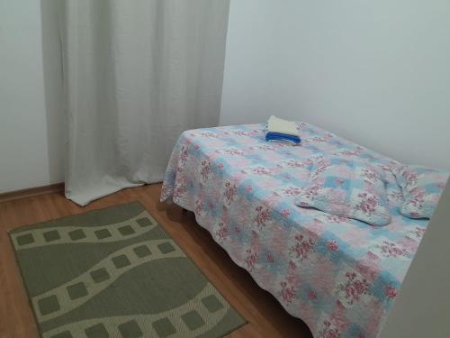 une chambre avec un lit avec une couverture et un tapis dans l'établissement Lar feliz, à Juiz de Fora