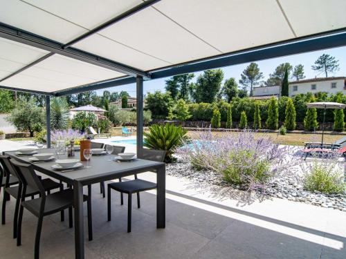 a patio with a table and chairs under a white umbrella at Holiday Home Villa D'Allongue by Interhome in Callian