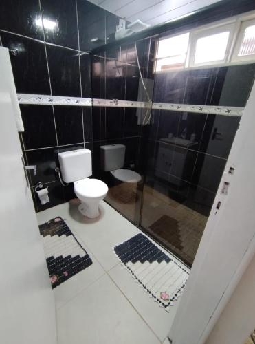 ein schwarz gefliestes Bad mit einem WC und einer Dusche in der Unterkunft Apartamento térreo em palhoça in Palhoça