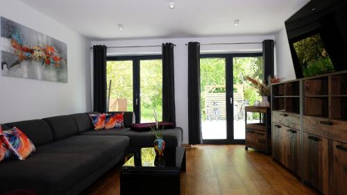a living room with a black couch and some windows at Ferienwohnung-Claudia in Schwerin in Schwerin