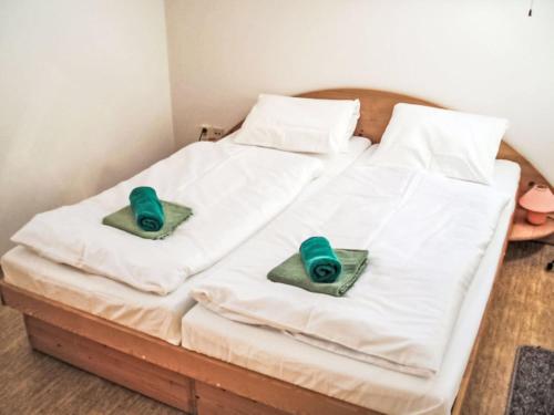 a white bed with two green pillows on it at Holiday Home Stárkov by Interhome in Stárkov