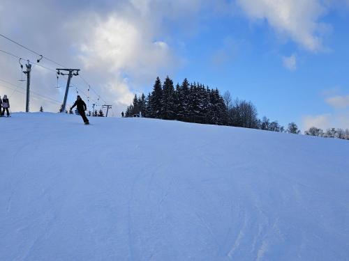 a person riding a snowboard down a snow covered slope at Holiday Home Stárkov by Interhome in Stárkov