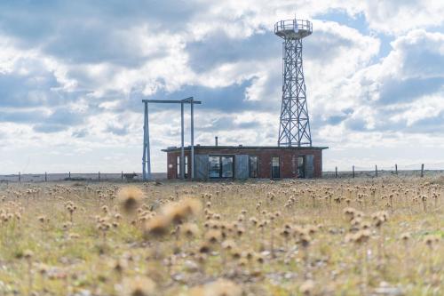 a building in the middle of a field with a tower at Fog Signal Building by Bloom Stays in Littlestone-on-Sea