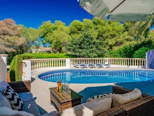 einen Pool mit Stühlen und einem Sonnenschirm auf einer Terrasse in der Unterkunft Holiday Home La Selva by Interhome in Jávea