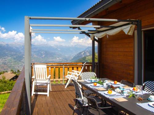 a table on a deck with a view of mountains at Holiday Home Chalet Mirabelle by Interhome in Nendaz