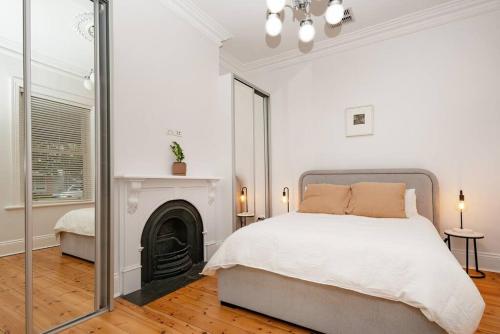 a white bedroom with a bed and a mirror at Essex Cottage with garden, 2BR, near Adelaide Showground in Wayville