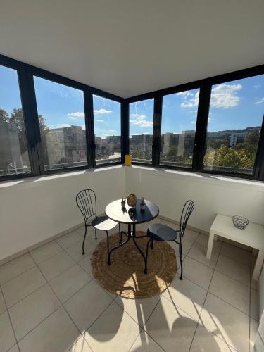 une table et des chaises dans une pièce avec des fenêtres dans l'établissement Appartement Cosy Lyon - Confluence, à Lyon