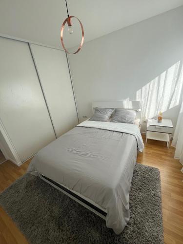 - une chambre blanche avec un grand lit et un tapis dans l'établissement Appartement Cosy Lyon - Confluence, à Lyon