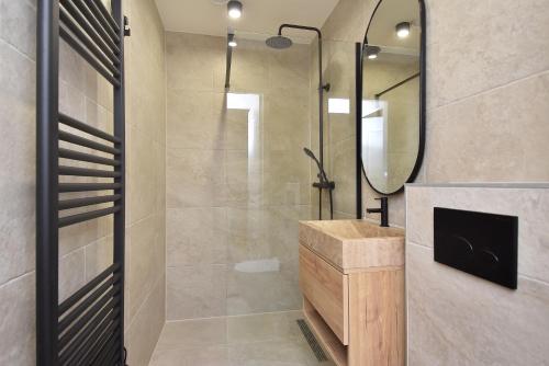 a bathroom with a shower with a sink and a mirror at Curated apartment near Scheveningen beach in Scheveningen