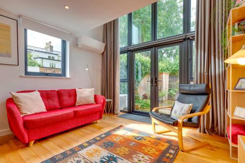 a living room with a red couch and a chair at 25A City Road · Luxury City centre townhouse with courtyard Pass the Keys in Cambridge