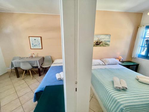 a bedroom with two beds and a dining table at Asterias Mini Coastal Apartments in Perivolos