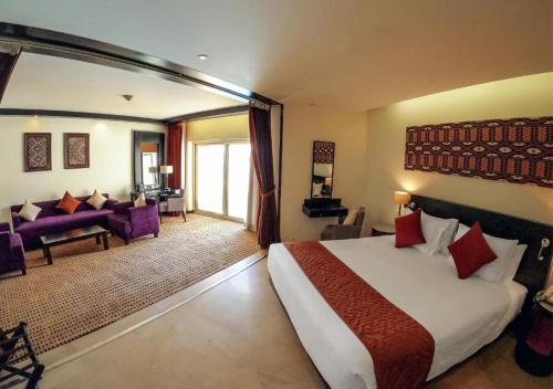 a bedroom with a large bed and a living room at Mövenpick Resort Aswan in Aswan