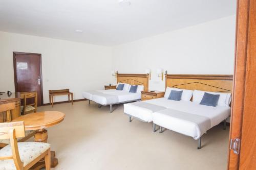 a room with two beds and a table and chairs at Alda Cabanas Playa in Cabañas