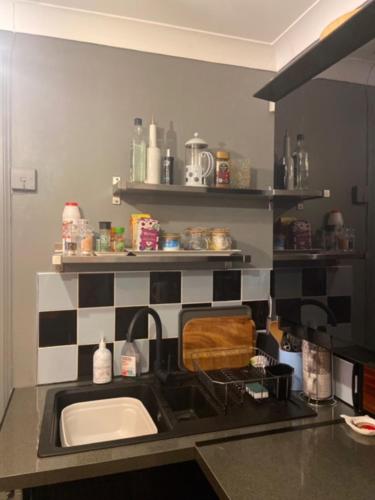 a kitchen with a sink and black and white tiles at Daiches Braes Brunstane Portobello in Edinburgh