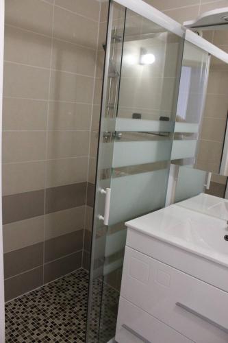 une salle de bain avec une douche en verre et un lavabo dans l'établissement Appartement T3 climatisé avec parking privatif proche plage - 5PSOL29, à Saint Cyprien Plage