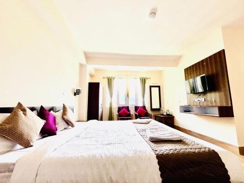 a bedroom with a large white bed with purple pillows at Hotel Swagat in Pelling