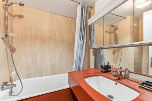 La salle de bains est pourvue d'un lavabo rouge et d'une baignoire. dans l'établissement Chic studio Champs-élysées, à Paris