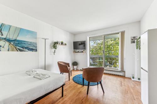 une chambre avec un lit et deux chaises et une fenêtre dans l'établissement Chic studio Champs-élysées, à Paris