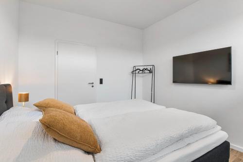 a white bedroom with a bed and a flat screen tv at 24-7 Living - Lüdinghausen Apartments in Lüdinghausen